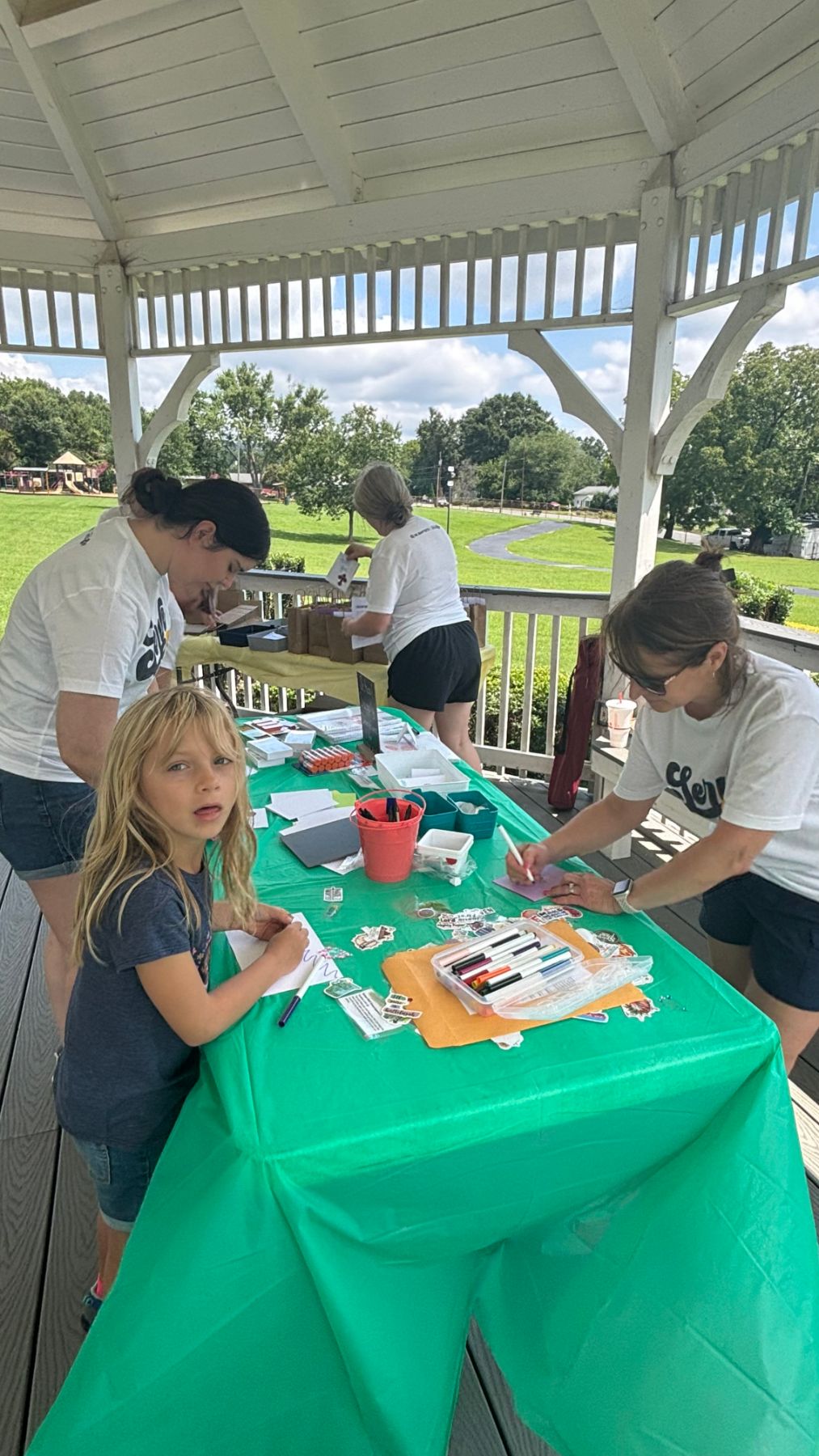 Children and volunteers making cards at a craft table in the park